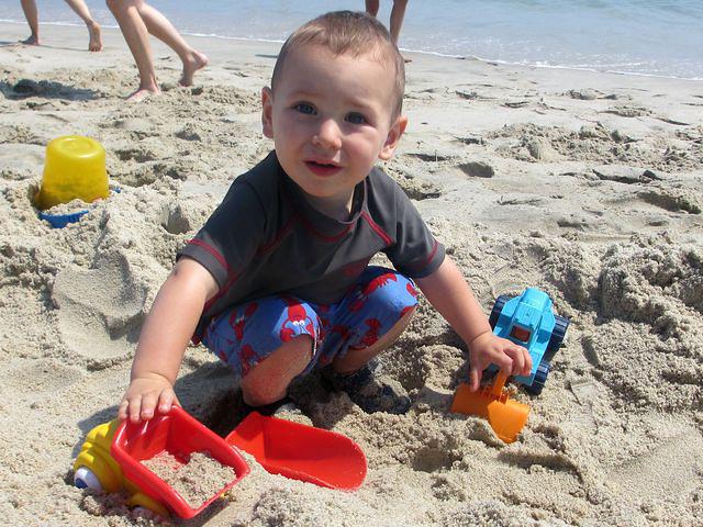 Thomas is happy to play wit his trucks on the beach